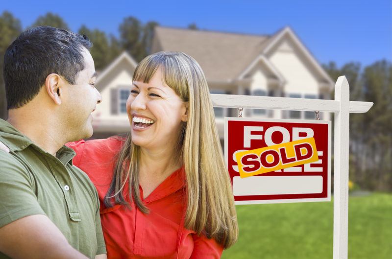 Oakland Couple in Front of Sold Real Estate Sold Sign and House