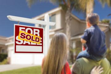 Family Facing Sold For Sale Real Estate Sign and House in Mobile, Alabama