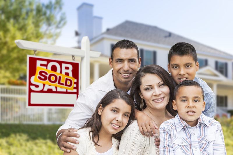 Photo of hispanic family in front of their L.A. house with sold sign.