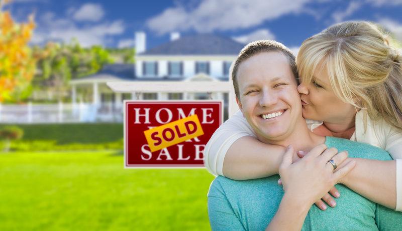 Minnesota Couple Kissing In Front of Sold Real Estate Sign and House