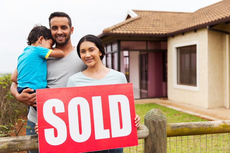 Indian family holding a sold sign outside their Michigan home