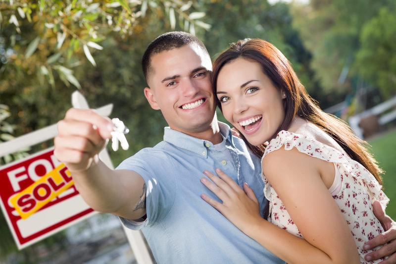 Military couple handing keys to house buyer after selling it