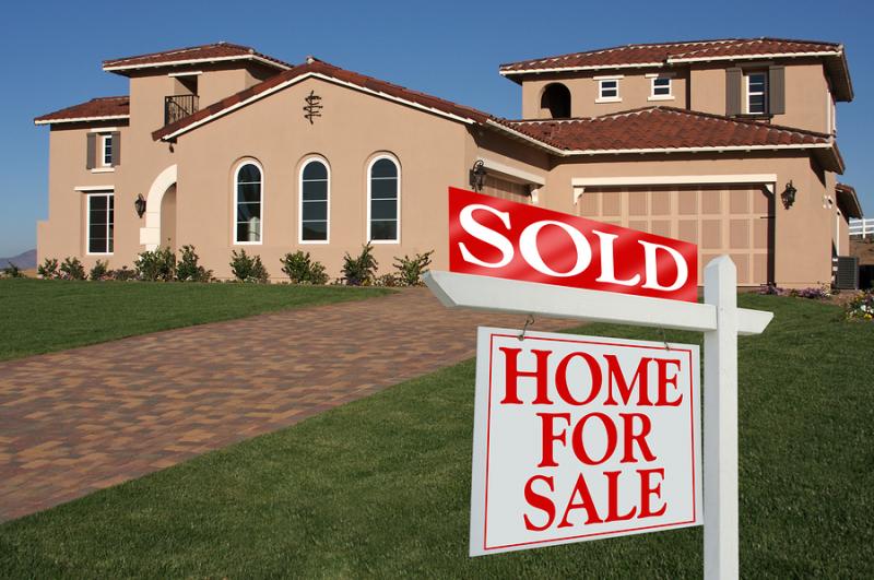 Big "Home For Sale" sign with "SOLD" addition in front of large California estate.