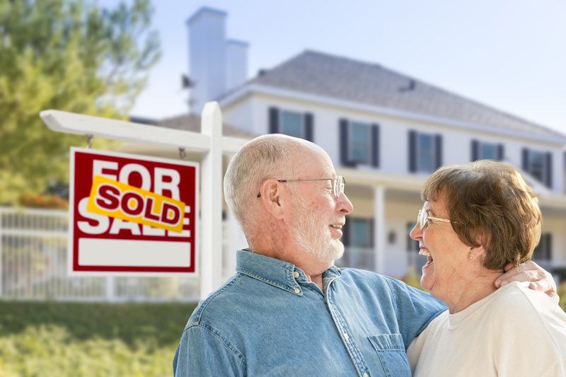 Senior California Couple in Front of Sold Real Estate Sign, House